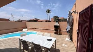 a patio with a table and chairs next to a pool at Anahi Homes Corralejo - Villa Drago 12 in La Oliva