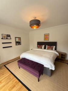 a bedroom with a large bed with a purple bench at Spacious 6 Bedroom house, Luton in Luton