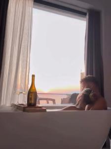 a man laying in a bed with a bottle of wine at Aloha Villa and Suites in Vlorë