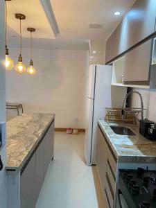 a kitchen with a white refrigerator and a counter top at Garden - San Marino in Ilhéus