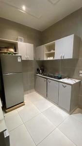 a kitchen with white cabinets and a refrigerator at Privée Cosy Moderne Equipée in Cotonou