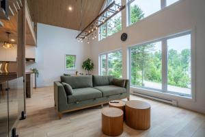 a living room with a green couch and some windows at Spa Babyfoot Total comfort - Le Chouette Chalet in Saint-Donat-de-Montcalm
