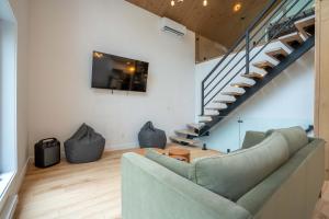 a living room with a couch and a staircase at Spa Babyfoot Total comfort - Le Chouette Chalet in Saint-Donat-de-Montcalm