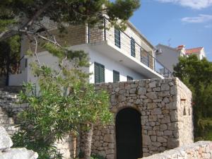 a white house with a stone wall and a building at Apartment Sanja in Primošten
