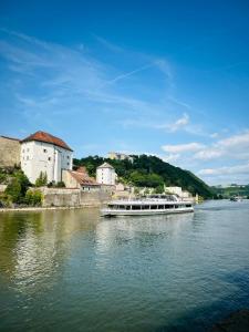 a boat traveling down a river near a building at The Cozy Corner - Passau in Passau