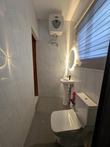 a white bathroom with a toilet and a sink at Abby and Gayle Rental Apartments in Apenkwa