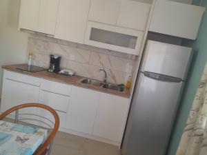 a kitchen with white cabinets and a refrigerator at Acheron Ripple by ΜΡS in Chóïka