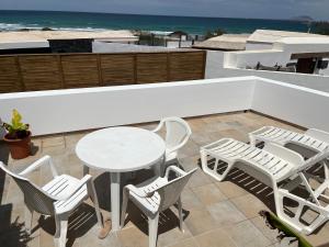 a patio with a table and chairs and the beach at Apartment in Famara Beach in Teguise