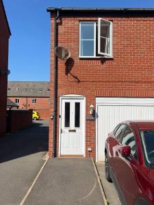 ダービーにあるDerby Luxury Apartment - Foss Road- Sleeps4の白い扉と車を持つ赤レンガ造りの家