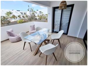 a dining room with a glass table and white chairs at Piso Volcano in Villaverde