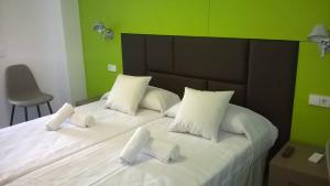a bedroom with a white bed with green walls at Huéspedes Sa Font in Ibiza Town