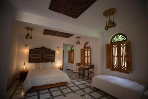 a bedroom with two beds and a table and windows at Riad Fez Medina in Fès +24 photos