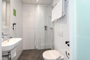 a white bathroom with a toilet and a sink at Court Garden Hotel in The Hague