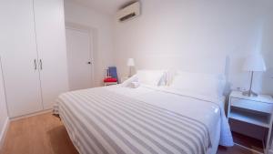 格拉纳达Piso Taracea的房间里有一张白色床，上面铺着条纹毯子。