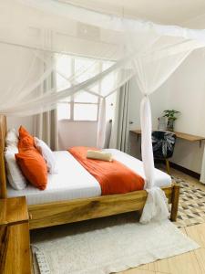 a bedroom with a canopy bed with orange and white pillows at Mkoani Homestay in Moshi
