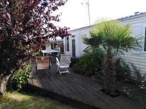 Saint-Nazaire-sur-CharenteにあるMobil Home 40 M², Proche De La Merの木製デッキ(テーブル、椅子付)