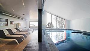 a swimming pool with a row of chairs in a building at Vacancéole - Les Chalets de l'Isard in Les Angles