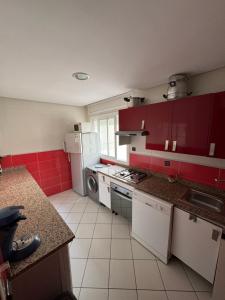 a kitchen with red and white cabinets and appliances at Residence avec piscine in Martil