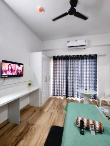 a living room with a ceiling fan and a flat screen tv at Kashu Luxury Stays in Greater Noida