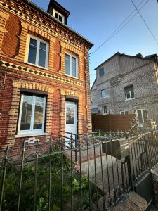 a brick house with a fence in front of it at Maison typique in Le Neubourg
