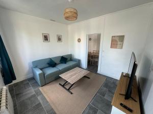 a living room with a blue couch and a table at Maison typique in Le Neubourg