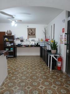 a kitchen with a counter and a table in a room at Pousada Parque Suites - Estacionamento e Piscina na Enseada in Guarujá