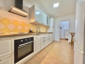 una cocina con armarios blancos y horno negro en Viva la Vida, en Los Realejos