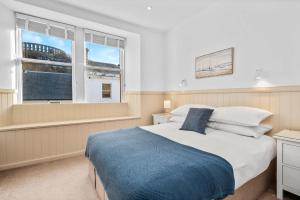 a bedroom with a large bed and two windows at Luxury 3BD Central Apt with Tower & Seaviews in Oban