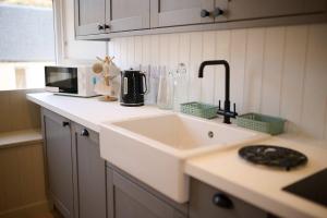 a kitchen counter with a sink and a microwave at Luxury 3BD Central Apt with Tower & Seaviews in Oban