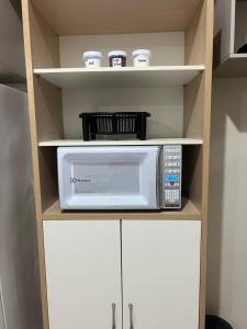 a microwave oven sitting on a shelf in a kitchen at Apartamento 2 quartos Completo in Novo Hamburgo
