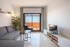 Una sala de estar con un sofá y un televisor. en Rock Bay II 2456 SEA VIEW, en Sotogrande