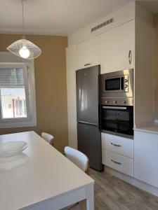 een keuken met een tafel en een roestvrijstalen koelkast bij Apartamento con huerta in San Mamede de Carnota +12 foto's