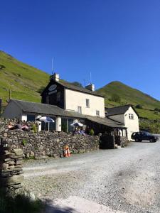 un edificio con persone sedute di fronte a un muro di pietra di The Brotherswater Inn a Patterdale