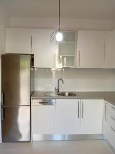 a kitchen with white cabinets and a stainless steel refrigerator at Apartman Anny in Široki Brijeg