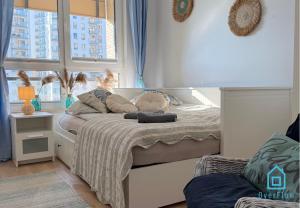 een slaapkamer met een wit bed met een raam bij Coast Apartment with Sauna & Gym, 5 Min to Baltic Sea & Polsat Plus Arena in Gdańsk