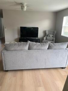 Better Than A 5 Star Hotel في ذا فيلاجيز: غرفة معيشة مع أريكة وتلفزيون