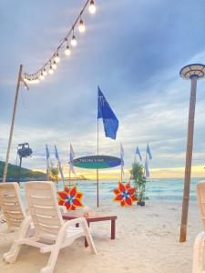 a beach with chairs and a table on the sand at The Sky & Sea Koh Larn in Ko Larn