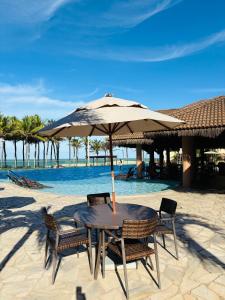 a table and chairs with an umbrella on the beach at Manhattan Beach Riviera 202 By AM in Aquiraz +27 photos