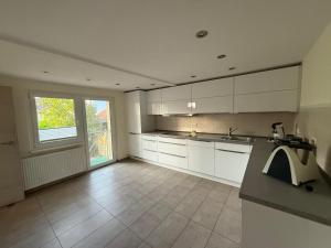 a kitchen with white cabinets and a large window at Casa Hortensia in Ettenheim