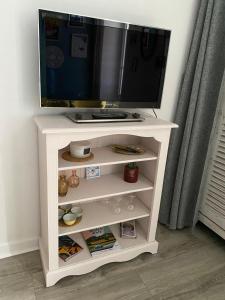 una tv in cima a un centro di intrattenimento bianco di Studio dans l'ancien Palace du Mont-Dore a Le Mont-Dore