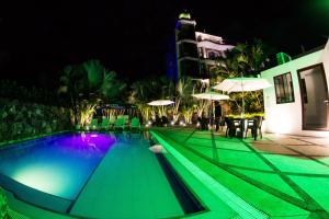 a swimming pool at night with tables and umbrellas at Dharma Beach in Montañita