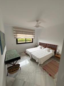 a white bedroom with two beds and a window at Las Colinas Beach in Manilva