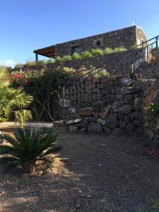 a stone retaining wall with a staircase and flowers at Dammuso Villa Giò in Pantelleria
