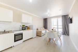 a white kitchen and dining room with a table and chairs at Красивые новые апартаменты in Astana