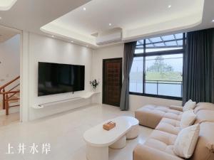 a living room with white furniture and a flat screen tv at Shangjing Waterfront Hotel in Dongshan