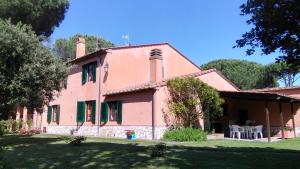 una antigua casa rosa con mesa y sillas en Agriturismo Sughericcio en Castagneto Carducci