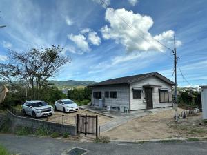 una casa con dos coches estacionados frente a ella en Taga House, en Awaji