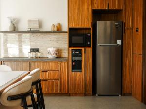a kitchen with a stainless steel refrigerator and wooden cabinets at Theolive Arrea - Spacious Private Pool and Backyard in Warung Menteng