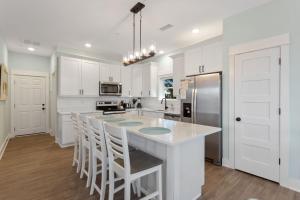 a kitchen with white cabinets and a island with bar stools at BCW32A - Sea Escape in Corolla +60 photos