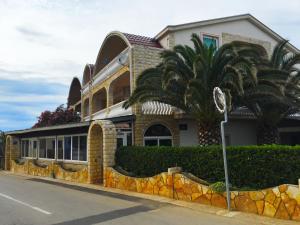 a house with a palm tree in front of it at Apartments Stojanovic in Vir